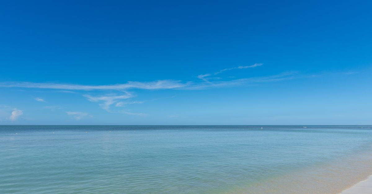 Viajera usando una eSIM en la playa Seven Mile Beach de Gran Caimán