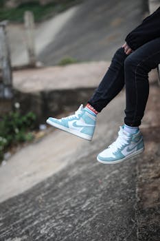 Close-up of blue Nike sneakers worn by a person sitting outdoors, showcasing a casual street style.