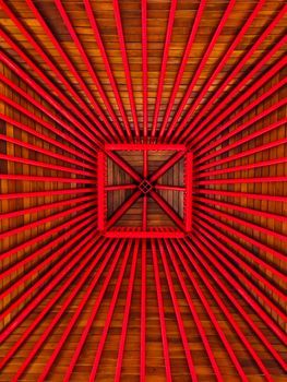 Bold red beams form a striking geometric pattern on a wooden ceiling.