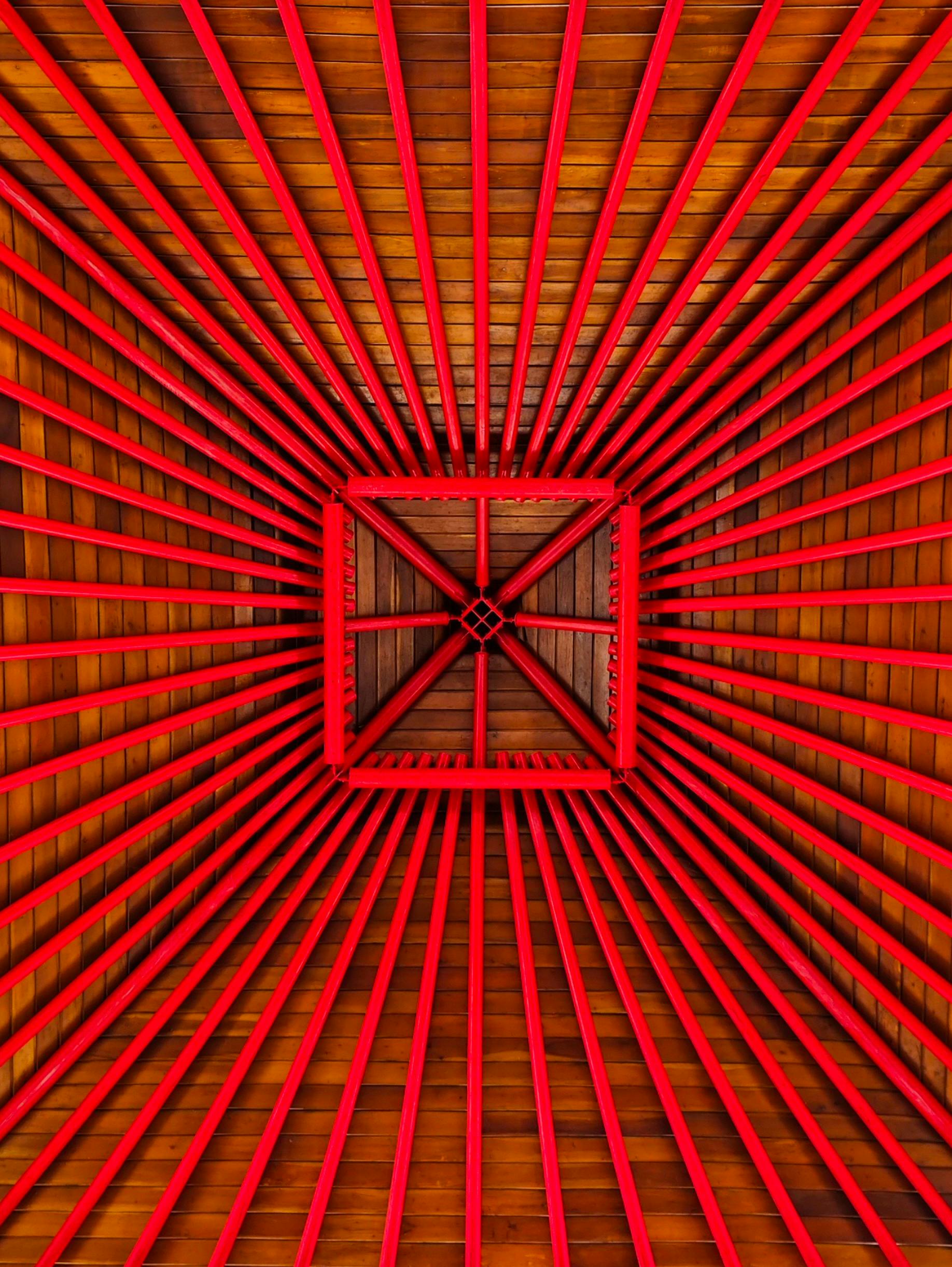 Gratuit Grinzi roșii îndrăznețe formează un model geometric izbitor pe un tavan din lemn. Fotografie de stoc