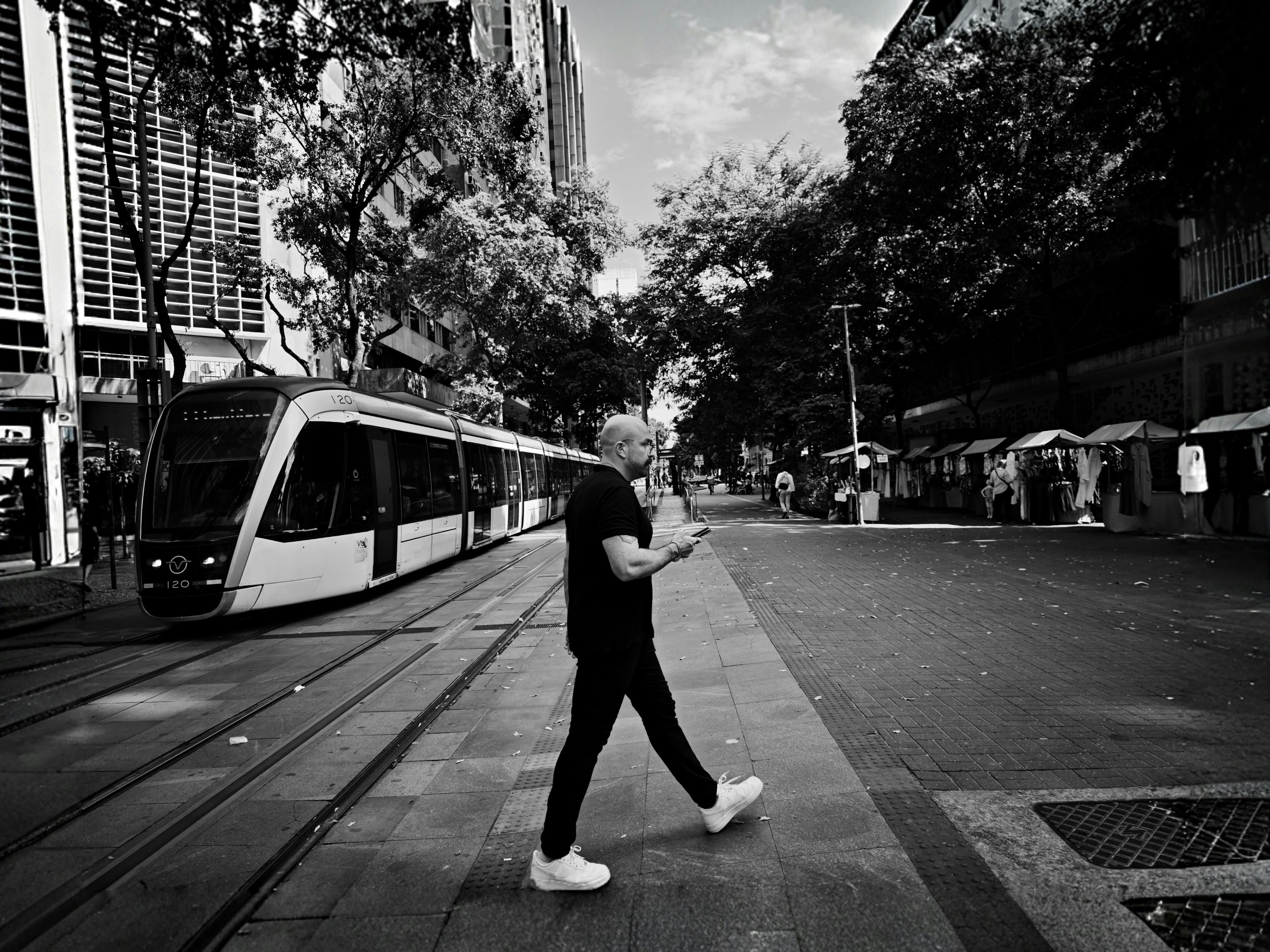Ücretsiz Rio de Janeiro'da tramvayın yakınında caddeden geçen bir adam (siyah beyaz fotoğraf). Stok Fotoğraflar