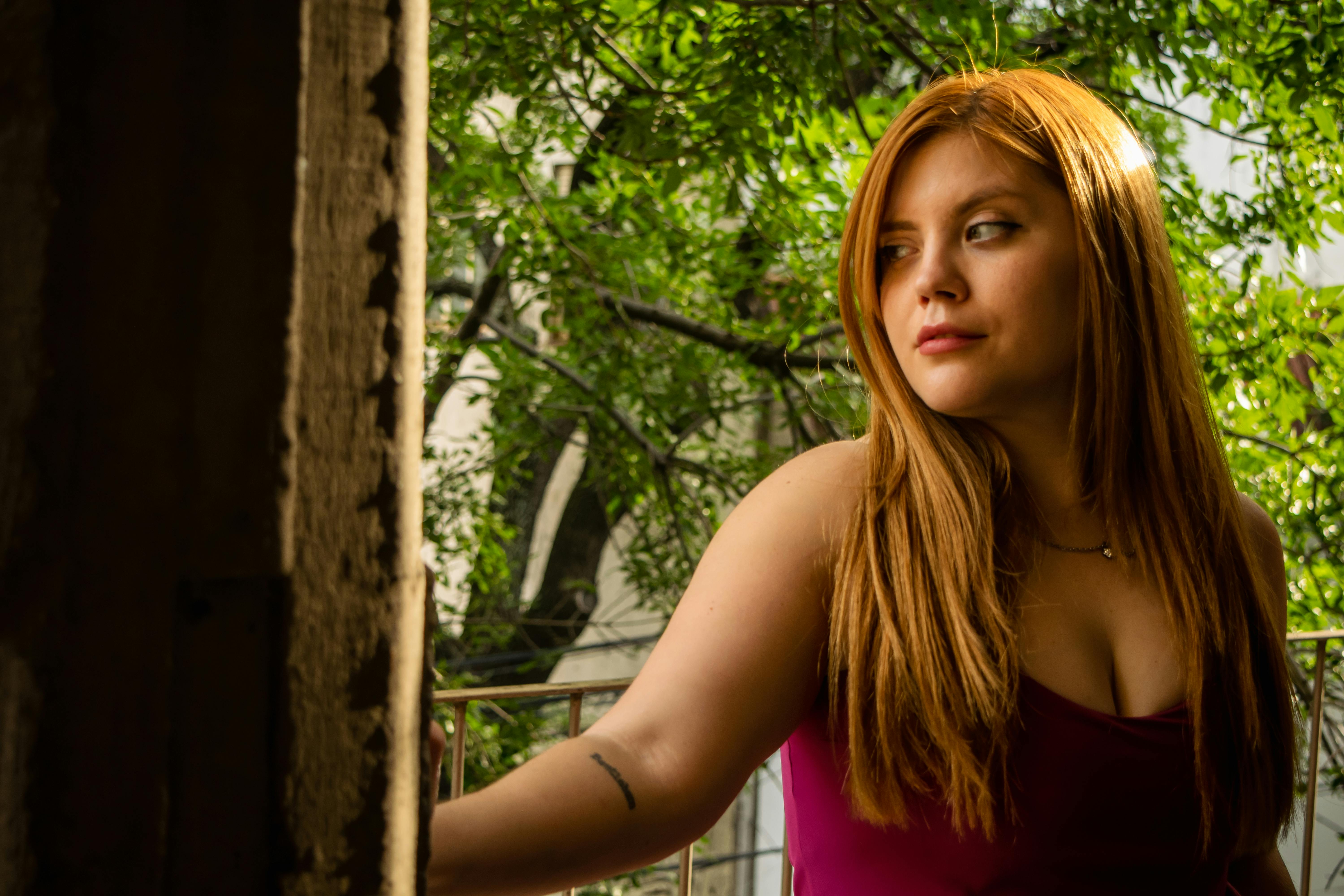 Δωρεάν Νεαρή γυναίκα ατενίζει έξω, περιτριγυρισμένη από πλούσια βλάστηση στο φως του ήλιου. Φωτογραφία από στοκ φωτογραφιών