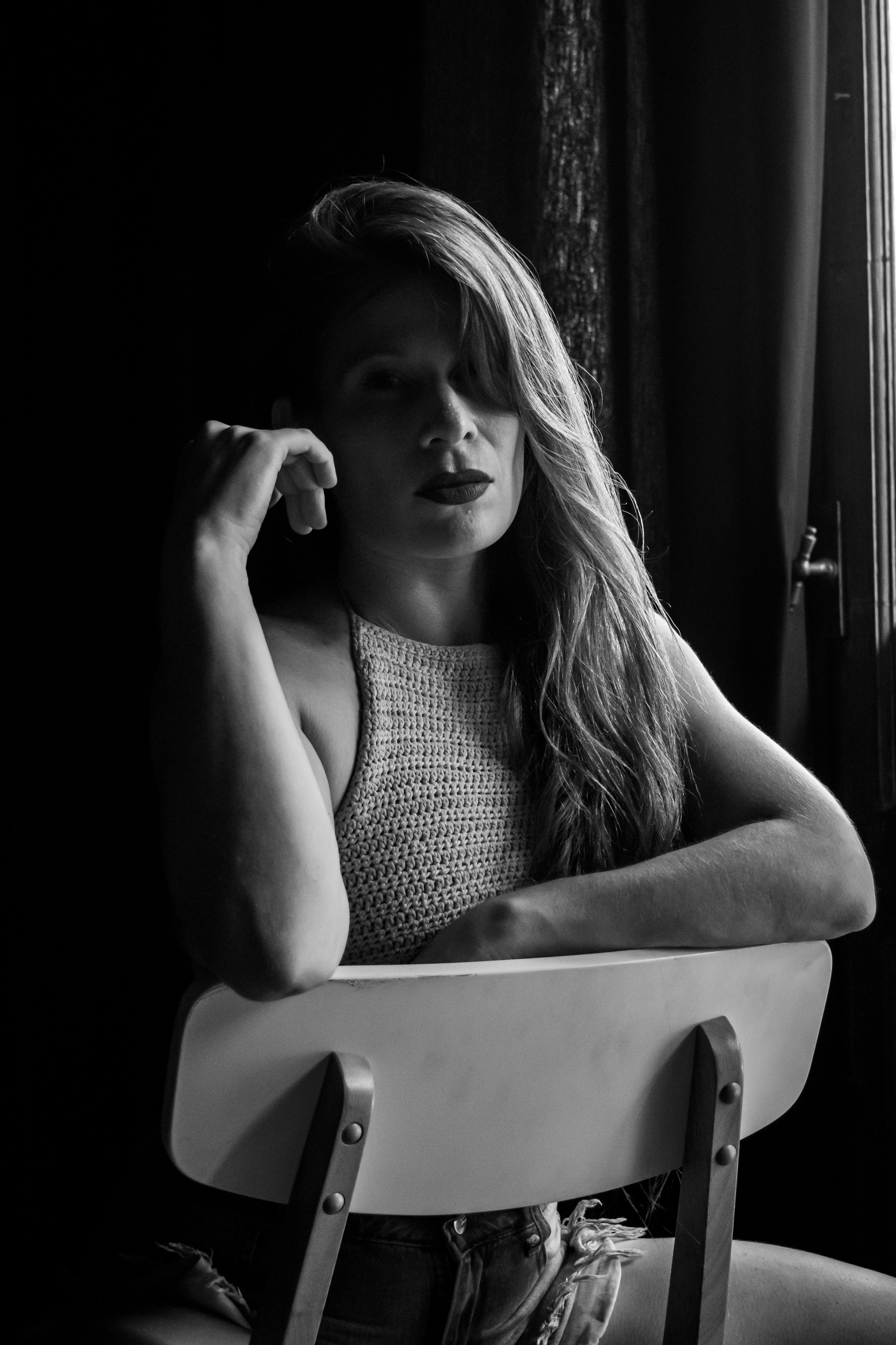 Free Artistic black and white portrait of a woman sitting on a chair, deep in thought. Stock Photo