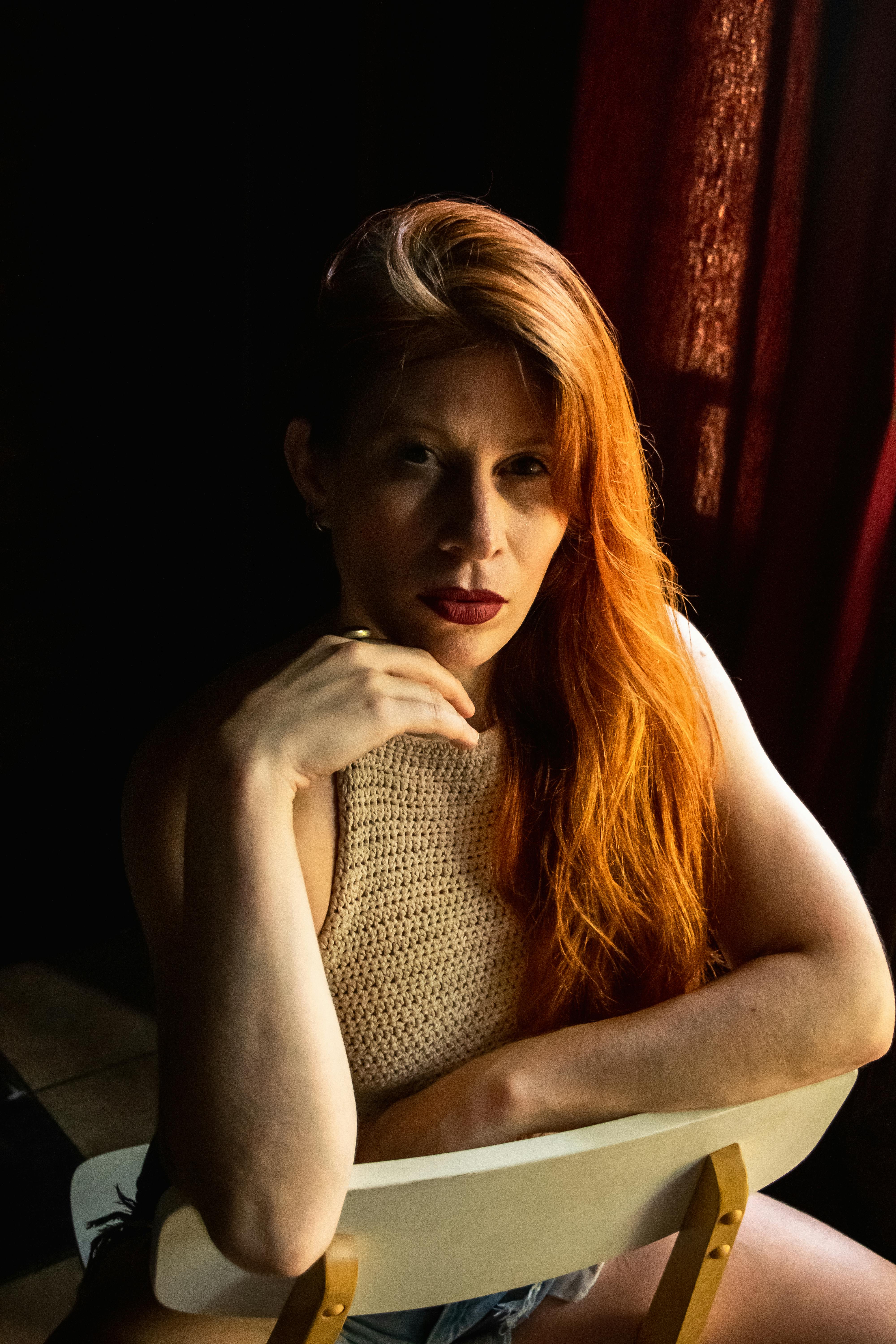 ฟรี ภาพถ่ายที่น่าสนใจของหญิงสาวผมแดงนั่งอยู่ภายในบ้านด้วยสีหน้าครุ่นคิด คลังภาพถ่าย