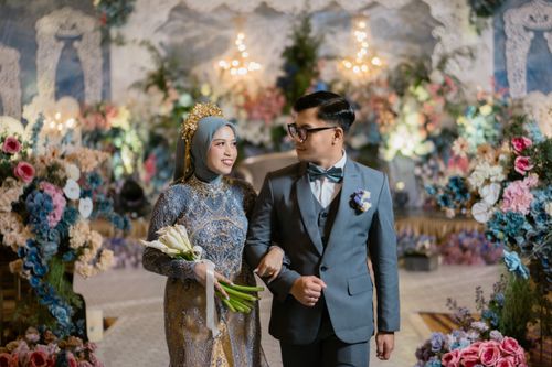 Free Stunning wedding couple in ornate attire with vibrant floral background, celebrating in Indonesia. Stock Photo