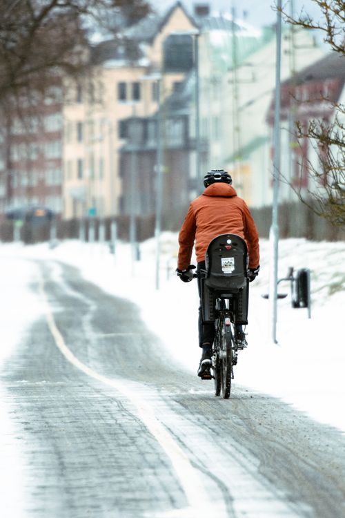 Free Adult cycling on snow-covered road in Jönköping, Sweden during winter. Stock Photo