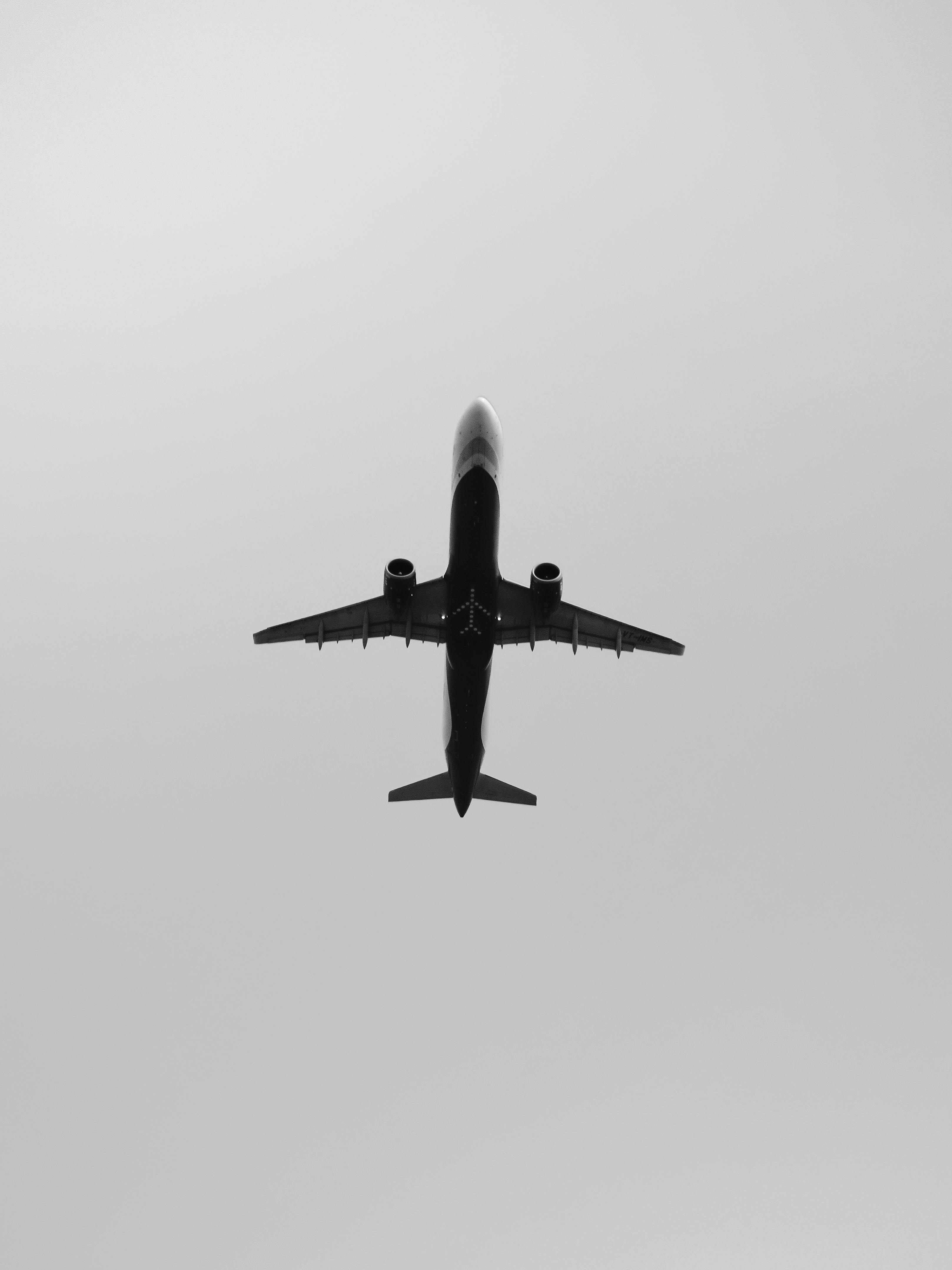 Free Monochrome image capturing a plane flying overhead against a clear sky. Stock Photo