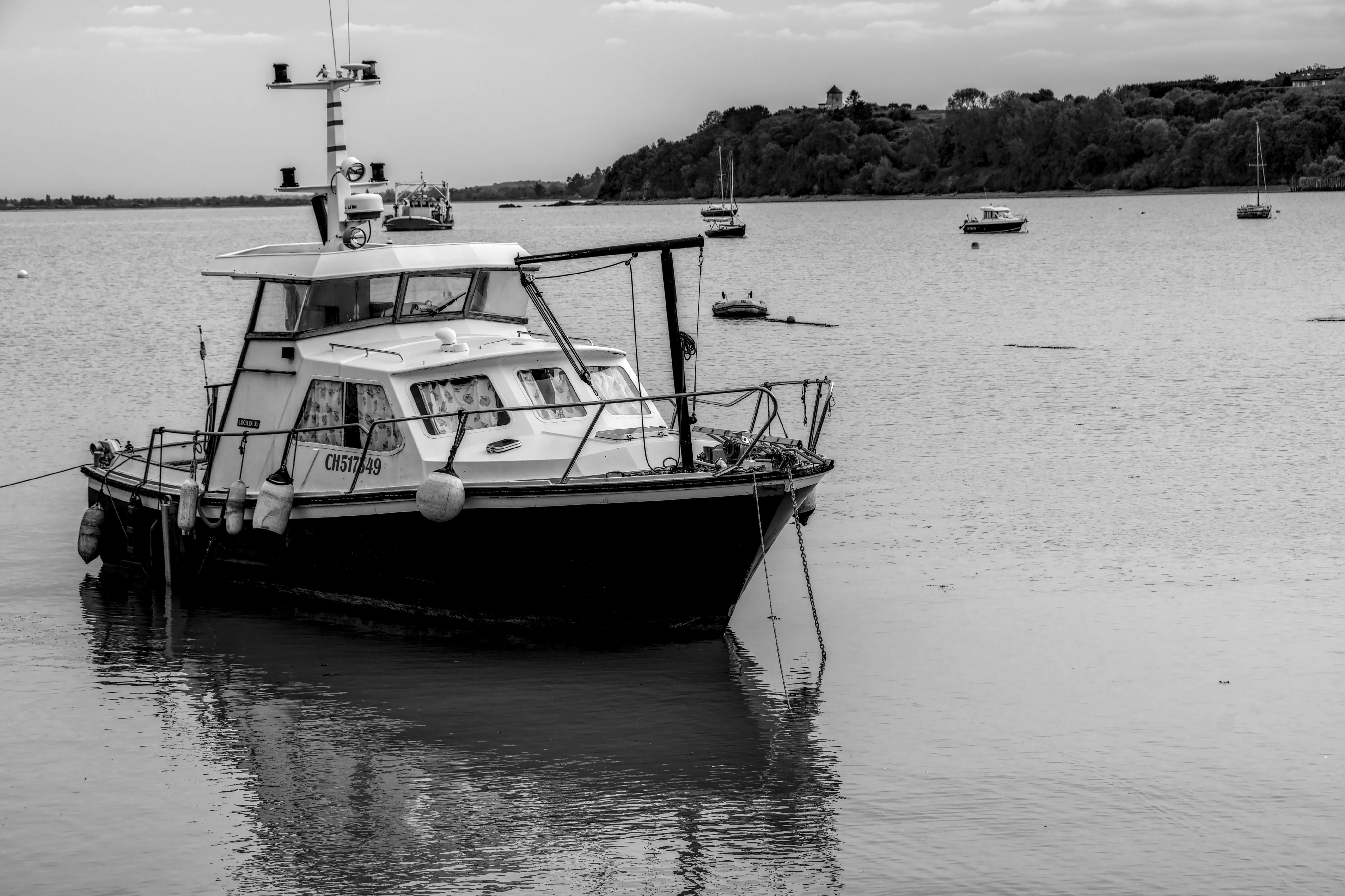 Δωρεάν Μια γαλήνια ασπρόμαυρη σκηνή ενός σκάφους αγκυροβολημένου σε έναν ήρεμο κόλπο, δημιουργώντας μια γαλήνια ατμόσφαιρα. Φωτογραφία από στοκ φωτογραφιών