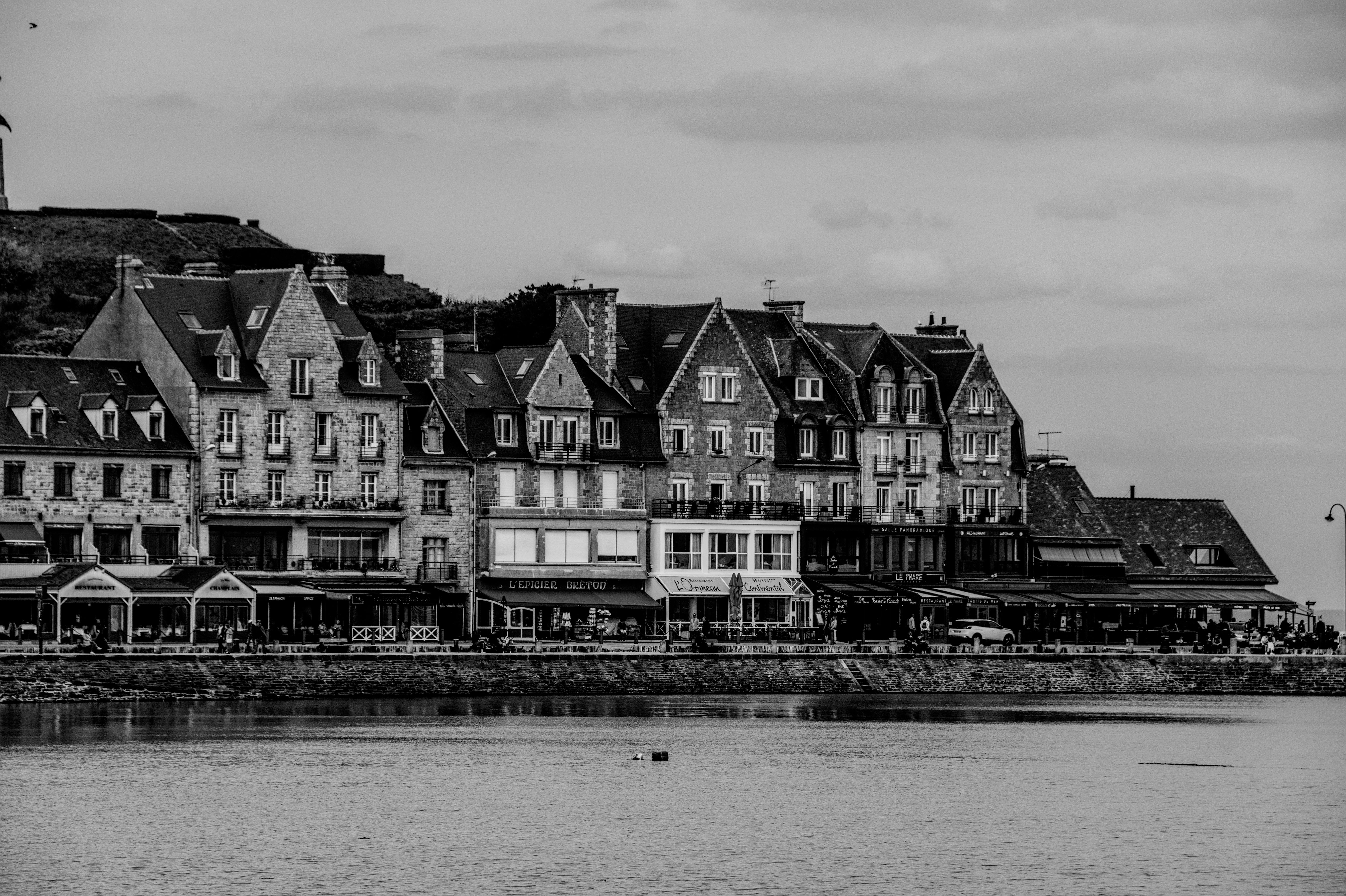 Black and white view of historic buildings along the coast in Brittany, France.