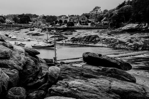 Free A black and white view of the rocky Brittany coastline with boats and traditional houses. Stock Photo