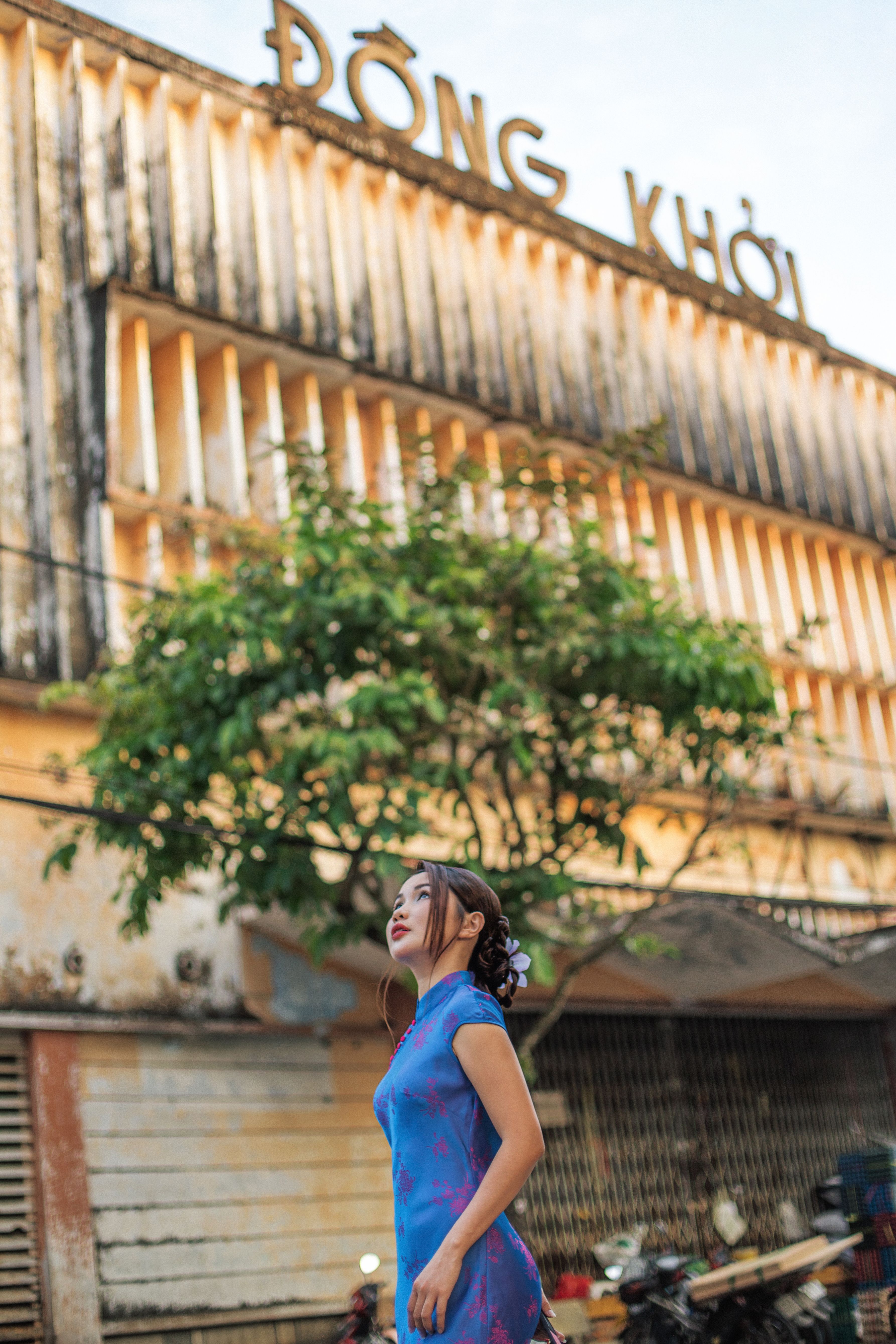 A woman in a blue traditional dress at Dong Khoi Street with a vintage backdrop.