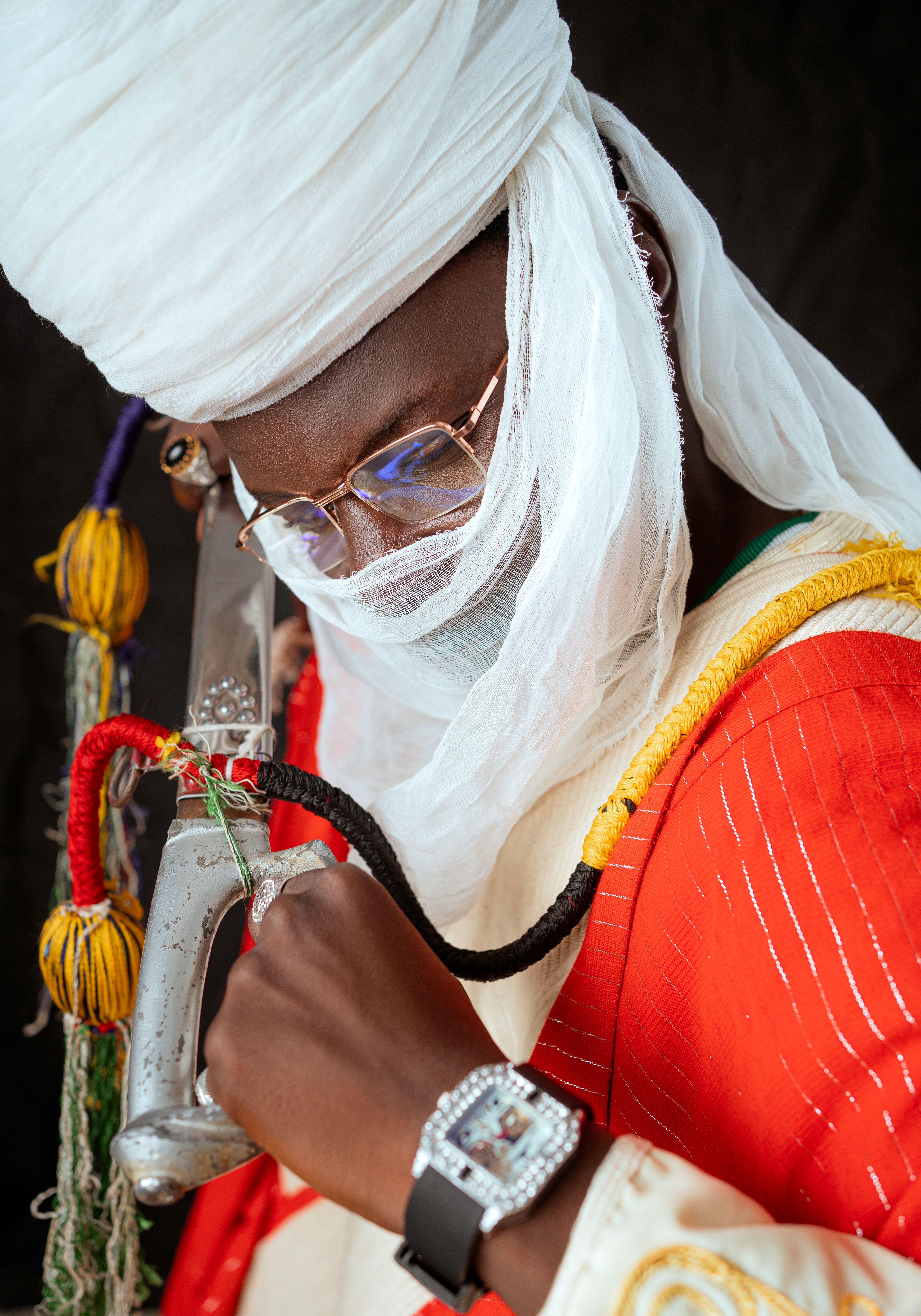 Close-up of a person in traditional attire with a colorful decorative sword and watch.