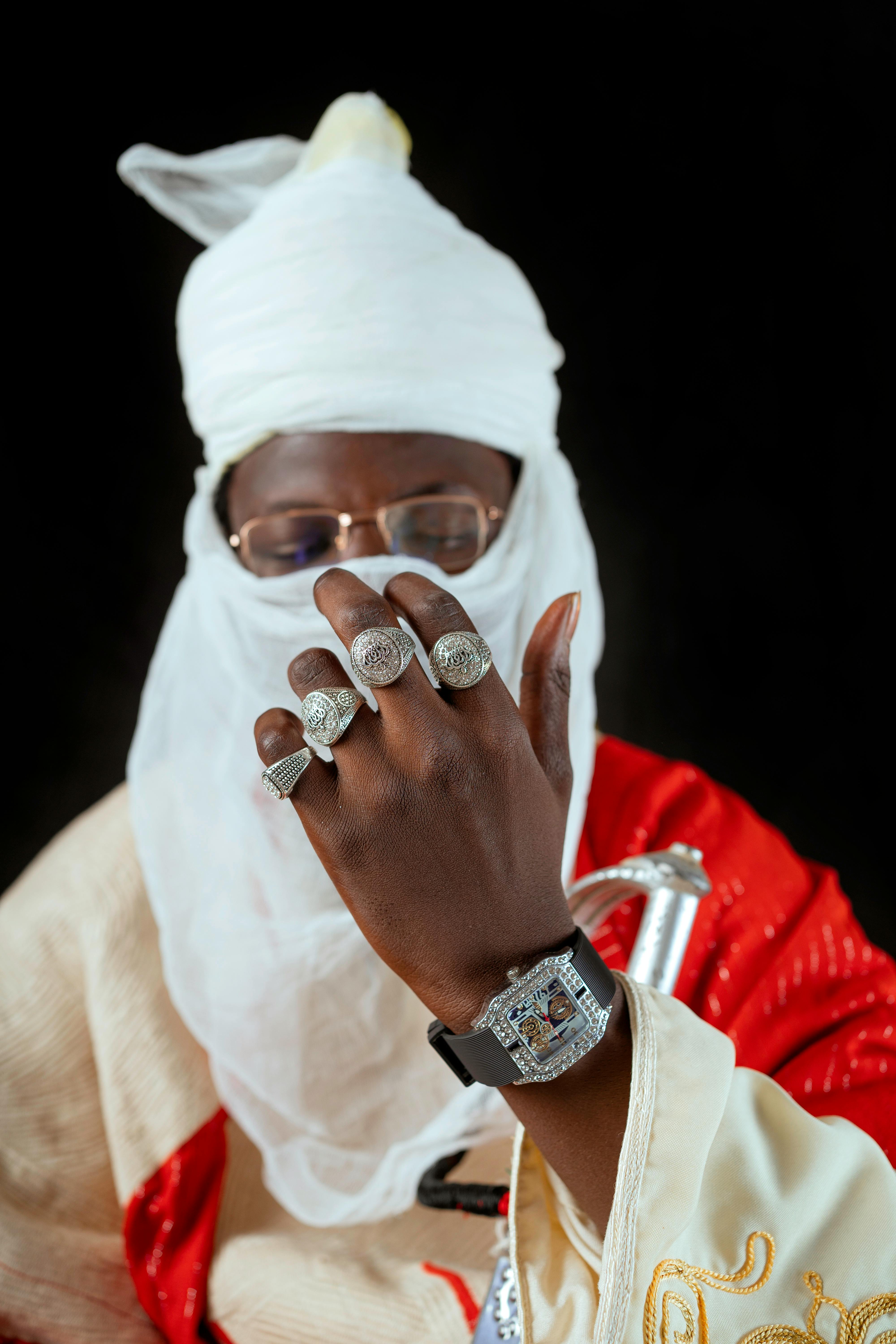 A person in traditional attire showcases ornate rings and a luxurious watch.