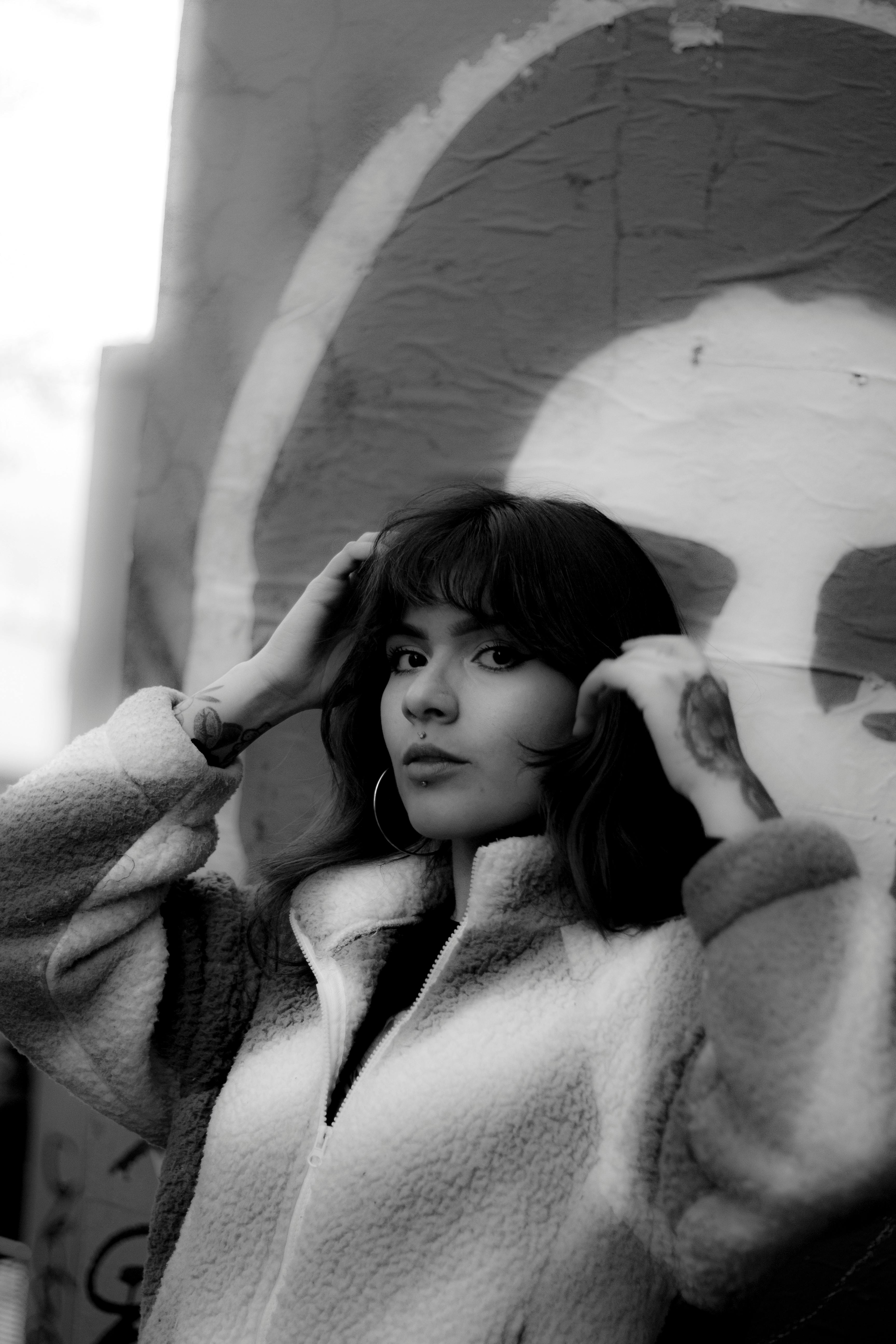 Gratis Et slående svart-hvitt-portrett av en kvinne som poserer selvsikkert mot en graffitivegg. Arkivbilde