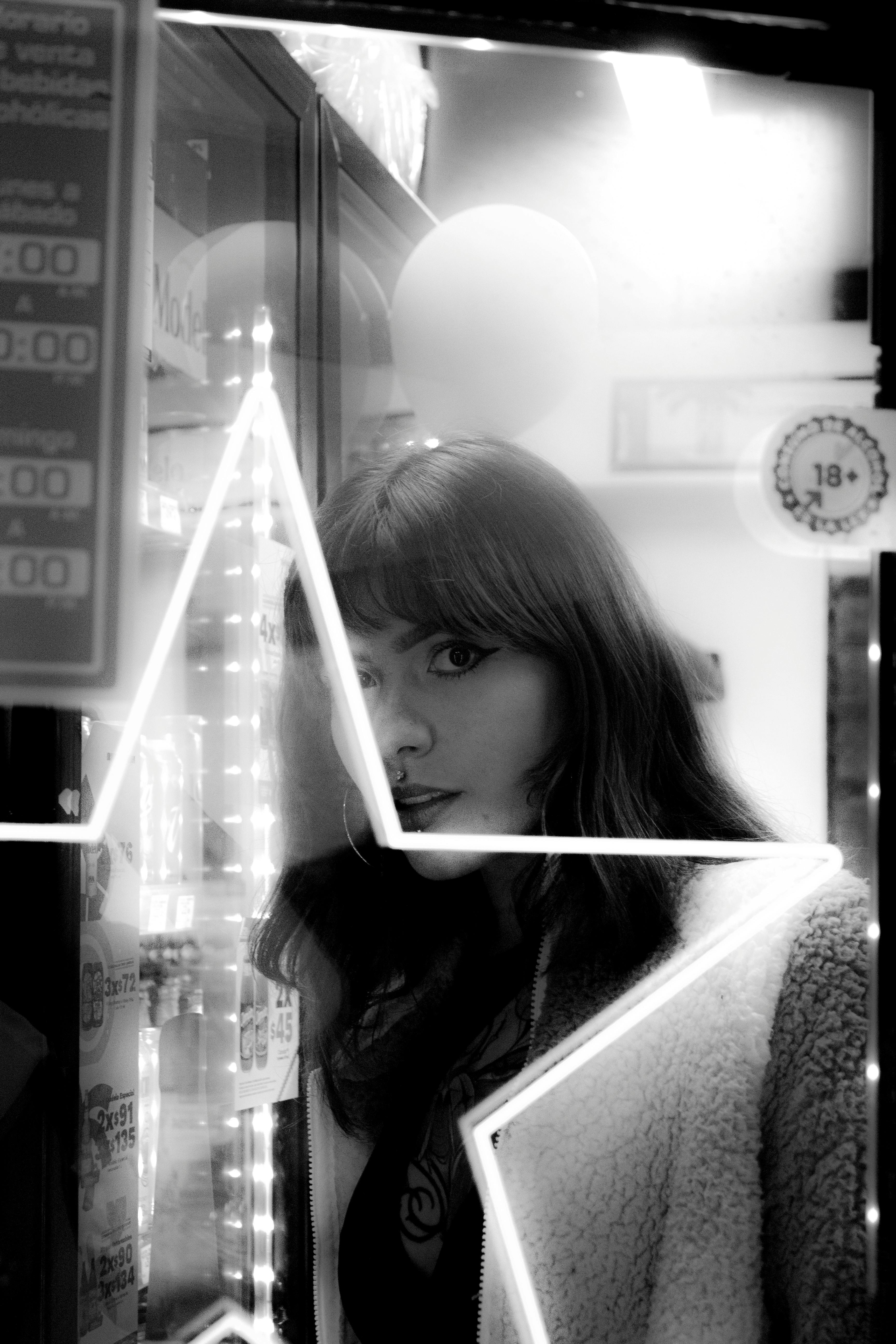 Free Moody black and white photo of a woman standing next to a store window in Toluca de Lerdo. Stock Photo