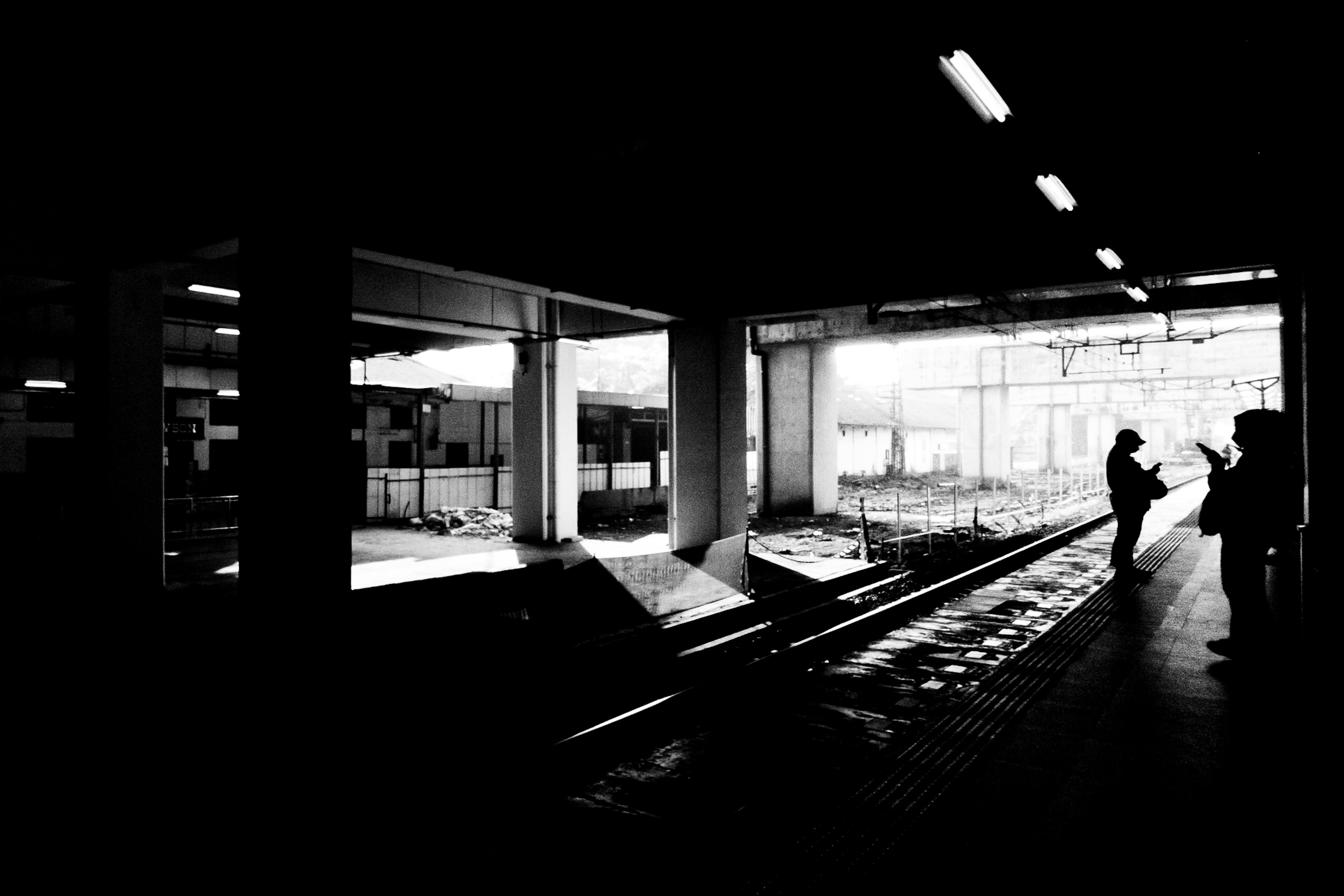 Gratis Silhuetter af figurer på Jakarta togstation, sort-hvid bystemning. Lagerfoto