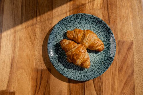 Free Two crispy croissants on a textured plate, perfect breakfast setup. Stock Photo