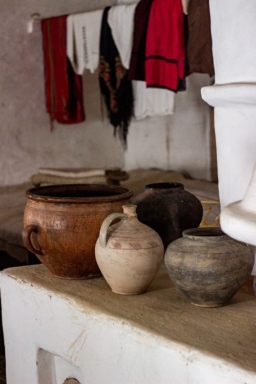 Free Traditional clay pots displayed on a rustic surface with historic textiles in the background. Stock Photo