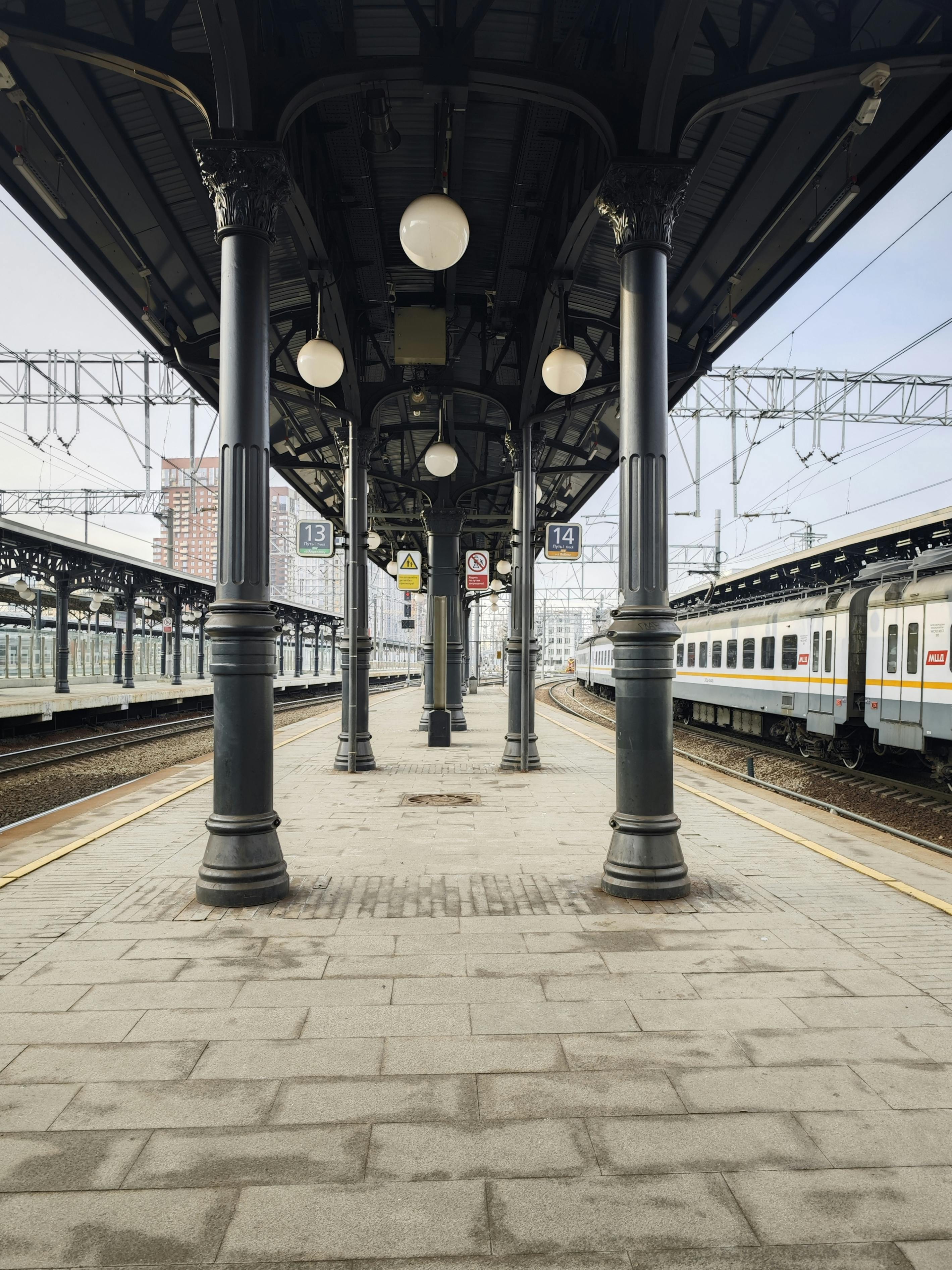 Δωρεάν Συμμετρική άποψη μιας κλασικής πλατφόρμας σιδηροδρομικού σταθμού με vintage λάμπες και τρένα που περιμένουν. Φωτογραφία από στοκ φωτογραφιών