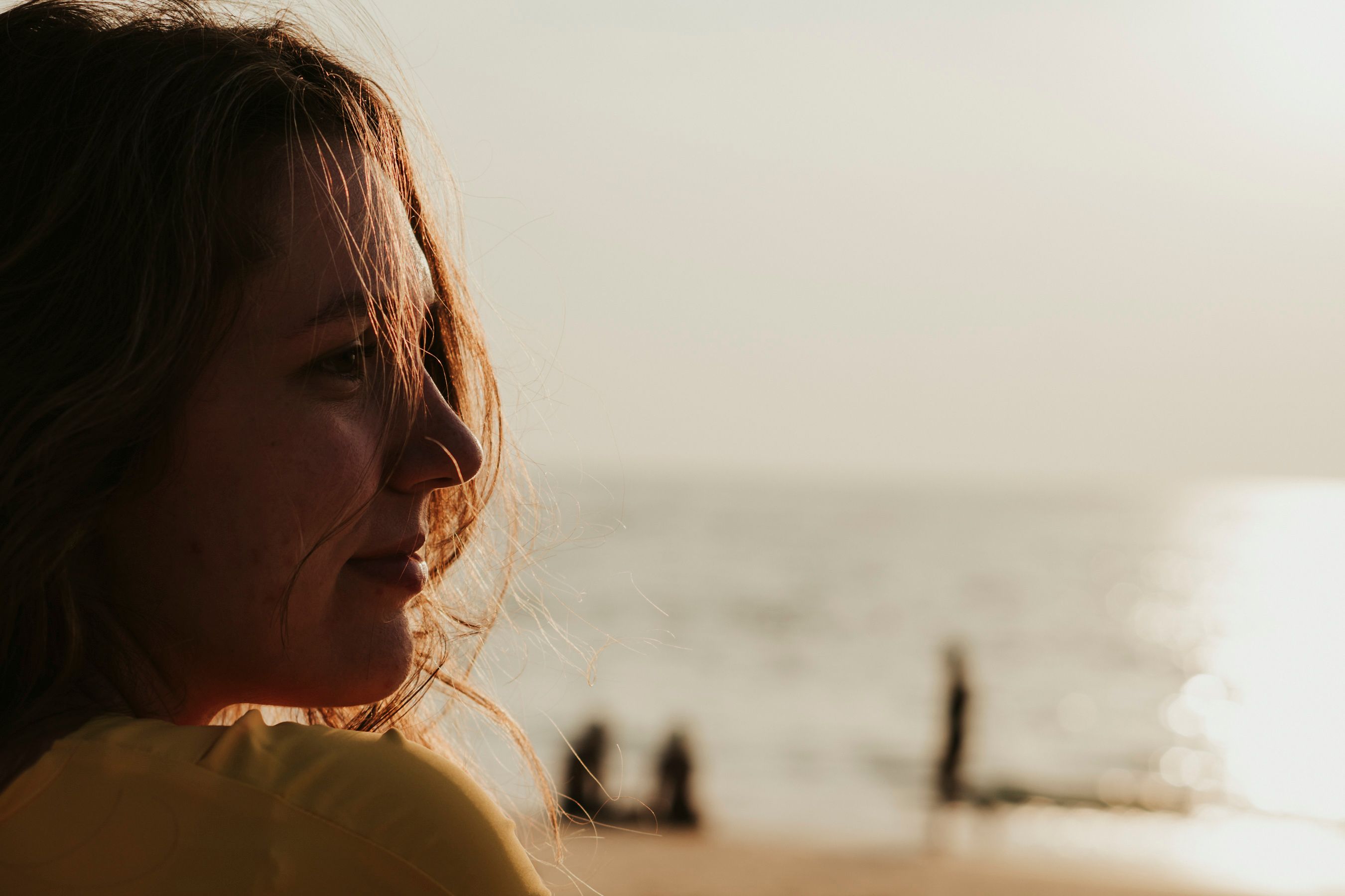 A serene portrait of a person gazing at the ocean during sunset on a Phuket beach.