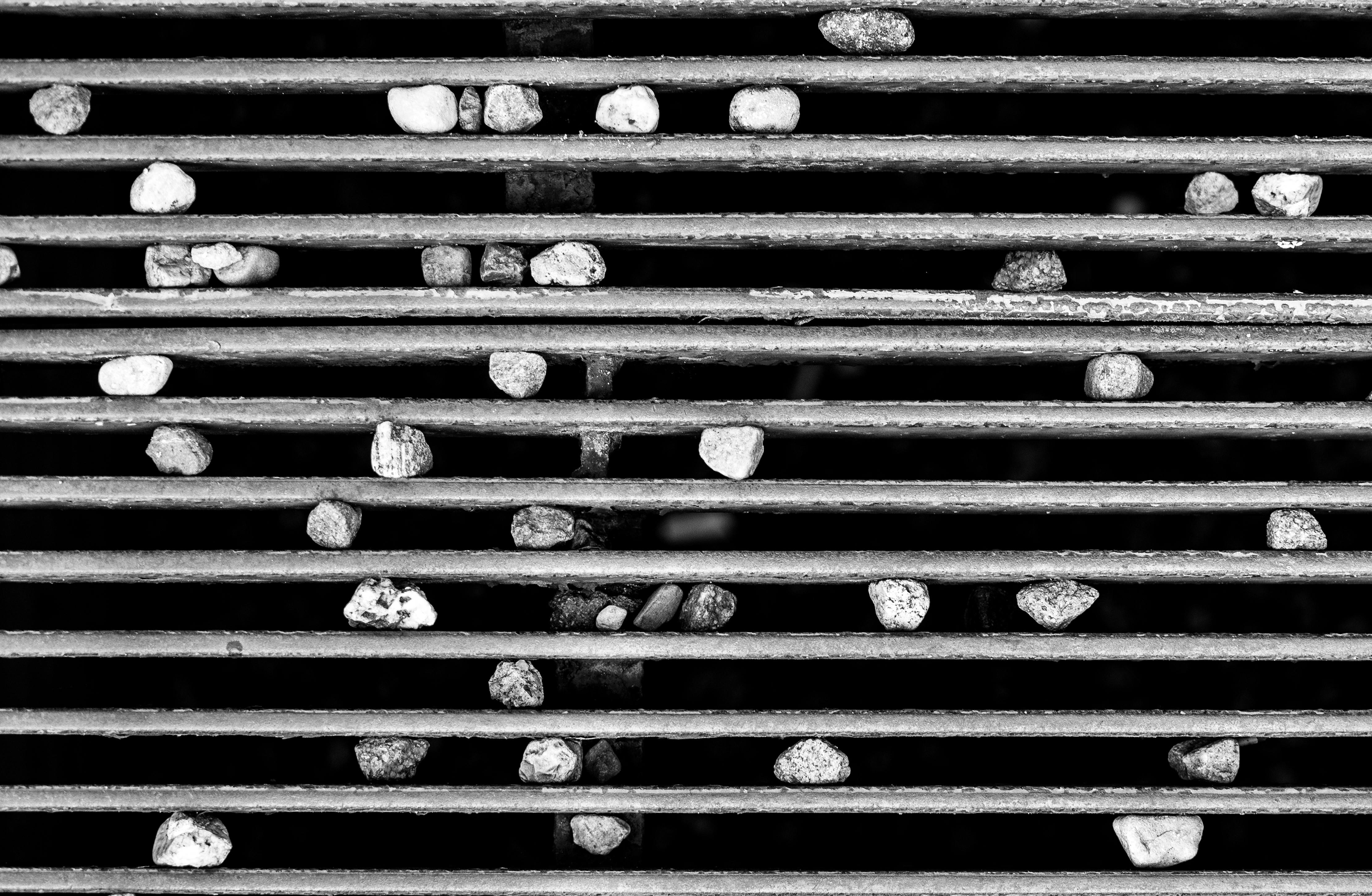 Ücretsiz Izgaralı bir yüzey üzerinde çakıl taşlarının oluşturduğu minimalist bir desenin sanatsal siyah beyaz fotoğrafı. Stok Fotoğraflar