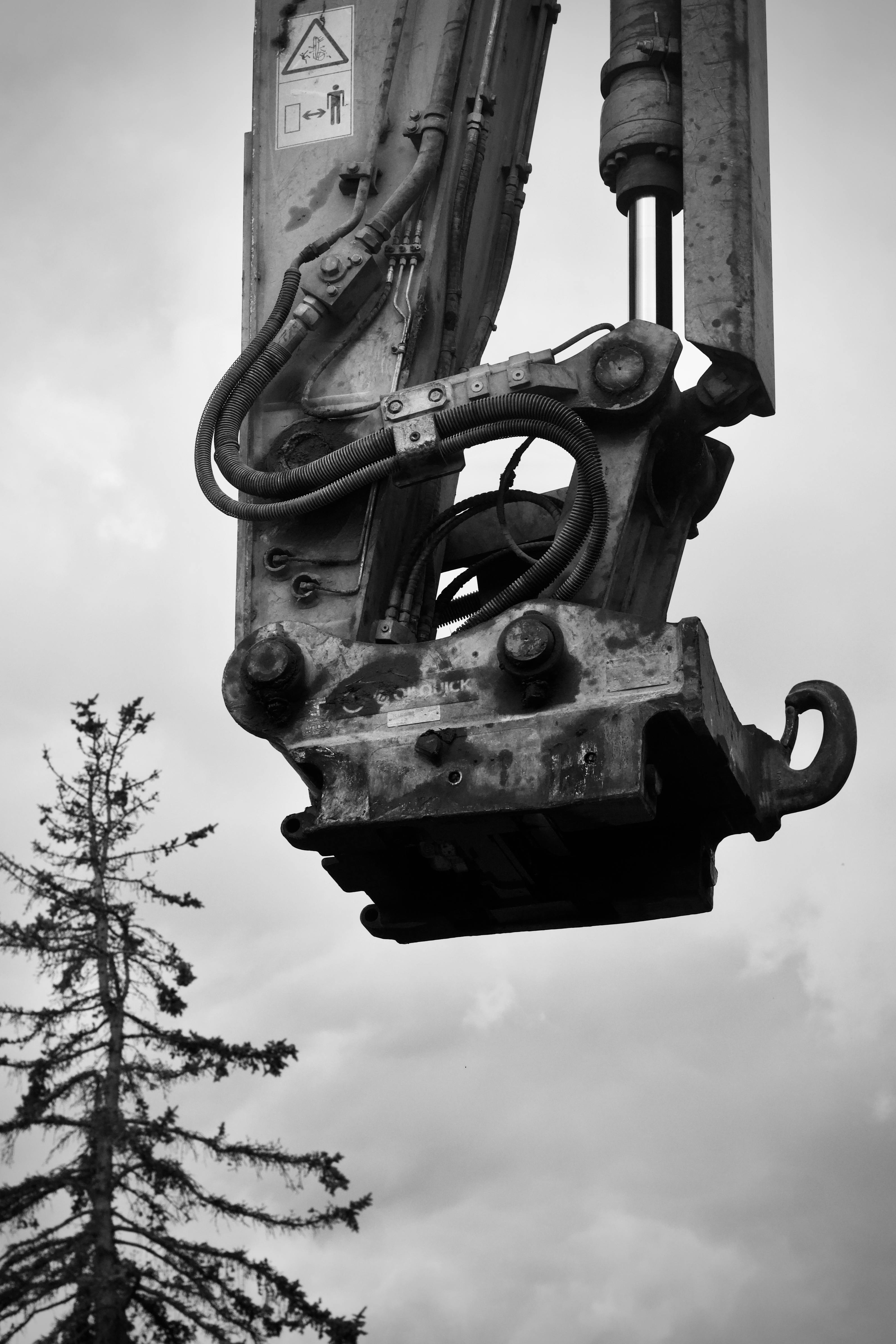 gratis Zwart-witfoto van een graafmachinearm met tandwielen en hulpstukken tegen een bewolkte hemel. Stockfoto