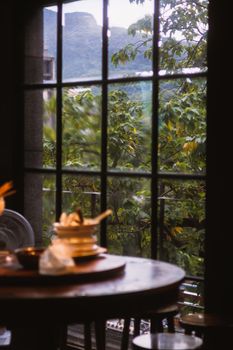 A quaint table by a window with a view of lush greenery outside, creating a serene dining ambiance.