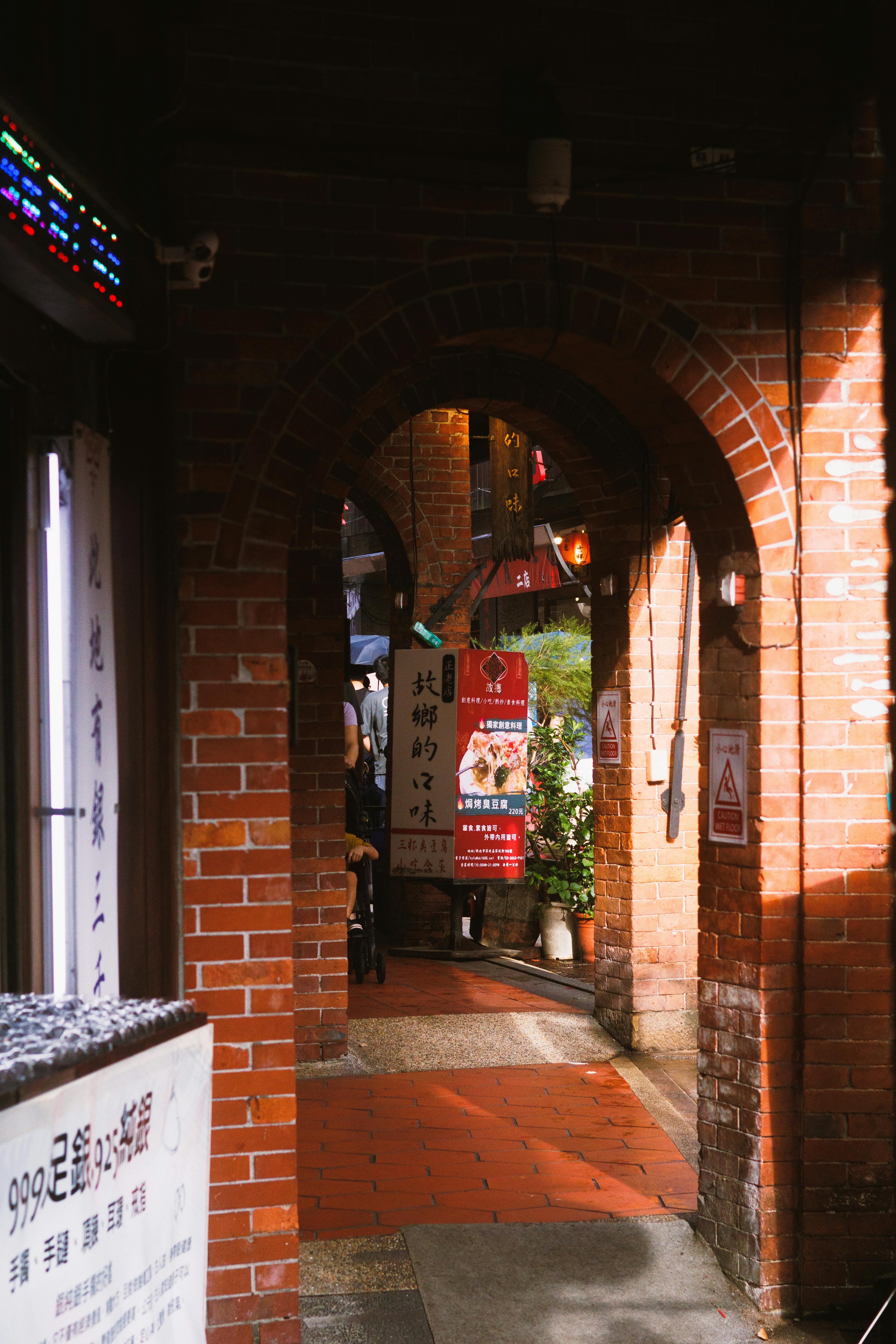 Ücretsiz Güneş ışığı Alan Ara Sokakta Rustik Tuğla Kemerli Giriş. Stok Fotoğraflar