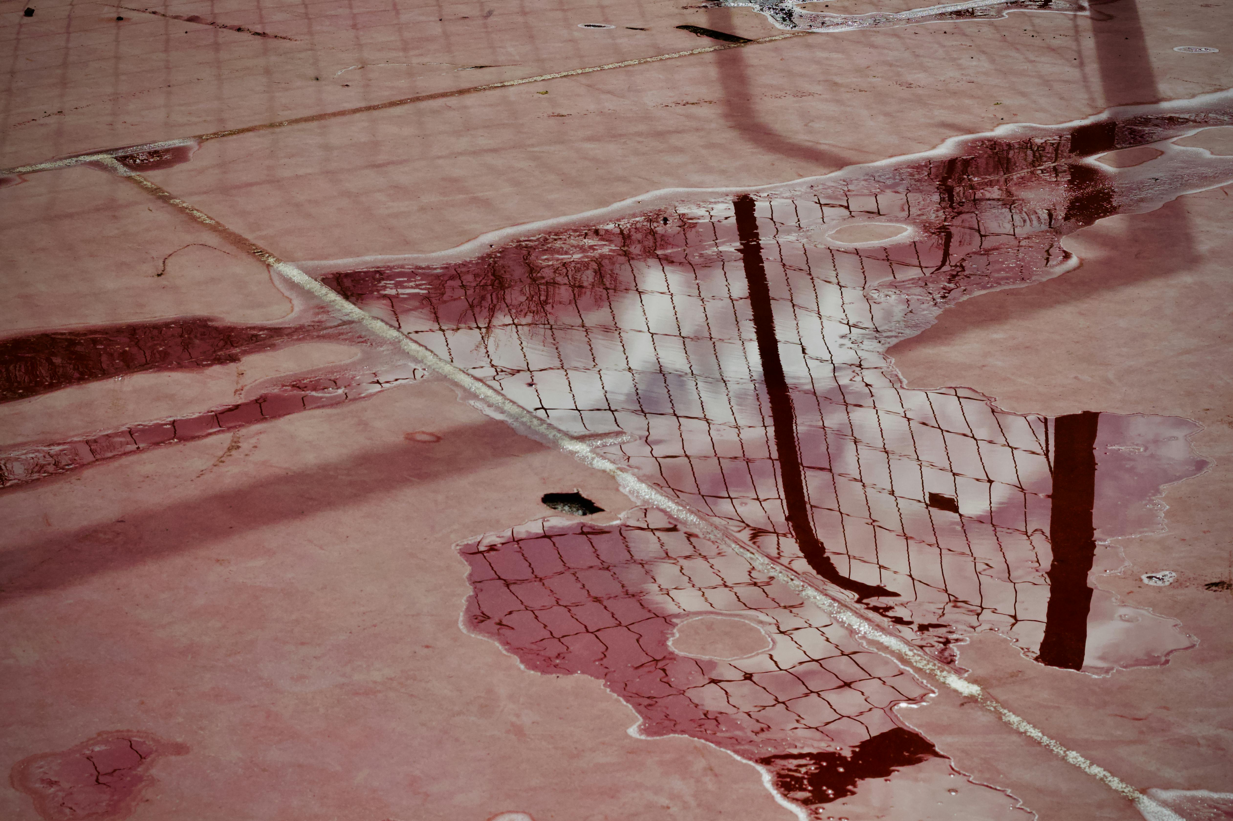Kostenlos Die Spiegelungen auf dem nassen Tennisplatz erzeugen ein abstraktes Muster mit einer gespenstischen Atmosphäre. Stock-Foto