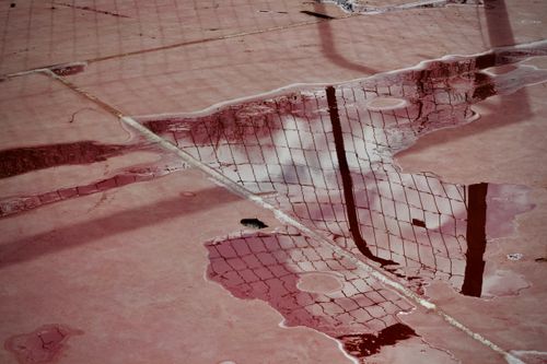 Free Reflections on a wet tennis court surface create an abstract pattern with a moody atmosphere. Stock Photo