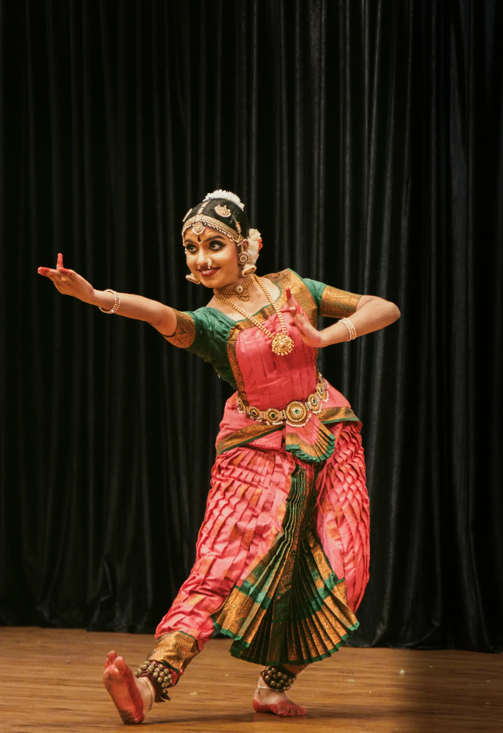 A Bharatanatyam dancer performing on stage in traditional attire