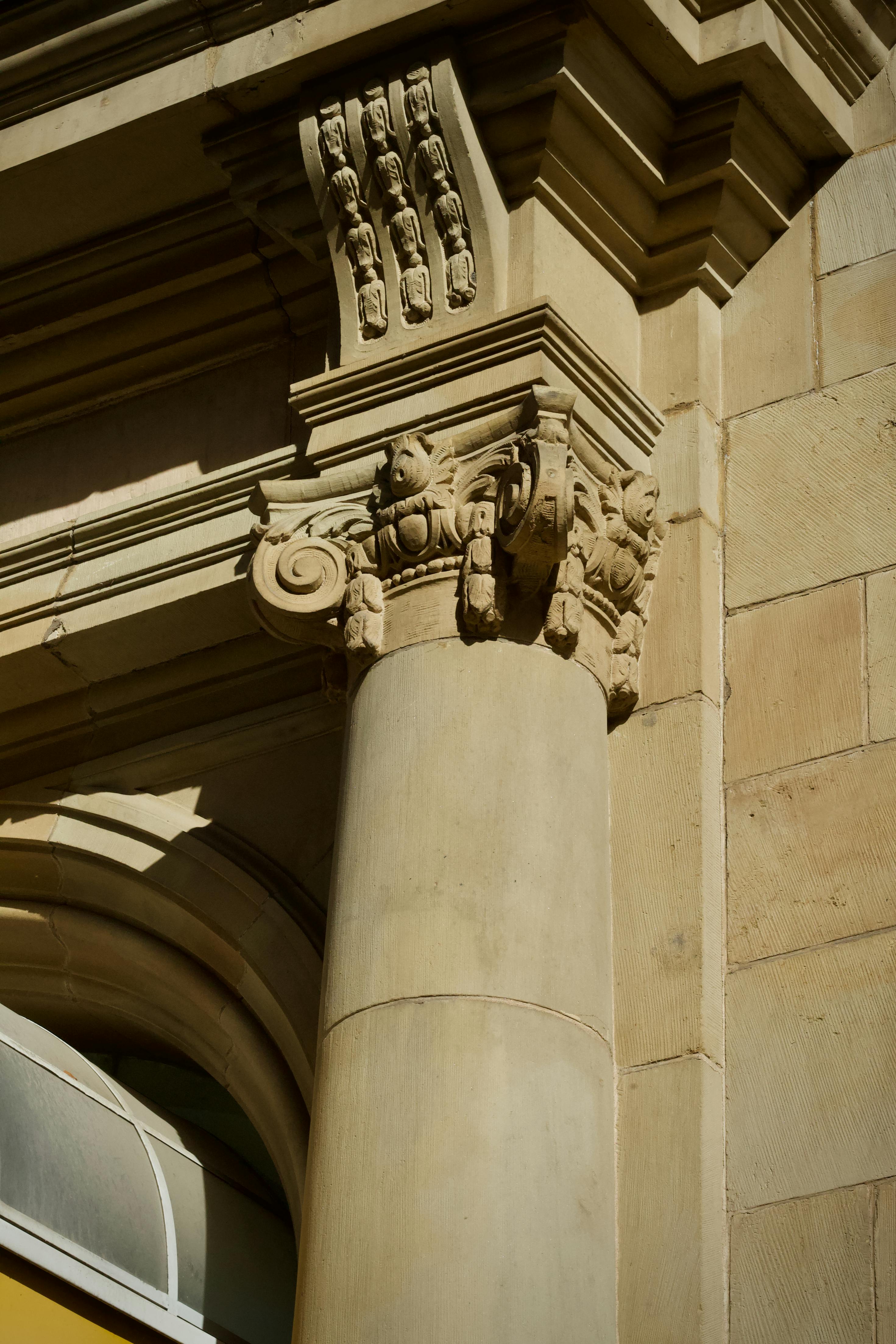 Bezpłatne Zbliżenie na klasyczną kolumnę architektoniczną ze szczegółowymi rzeźbami w świetle słonecznym. Zdjęcie z galerii