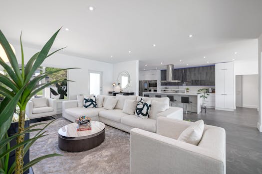 Elegant open-concept living room with kitchen, featuring modern decor and bright lighting.