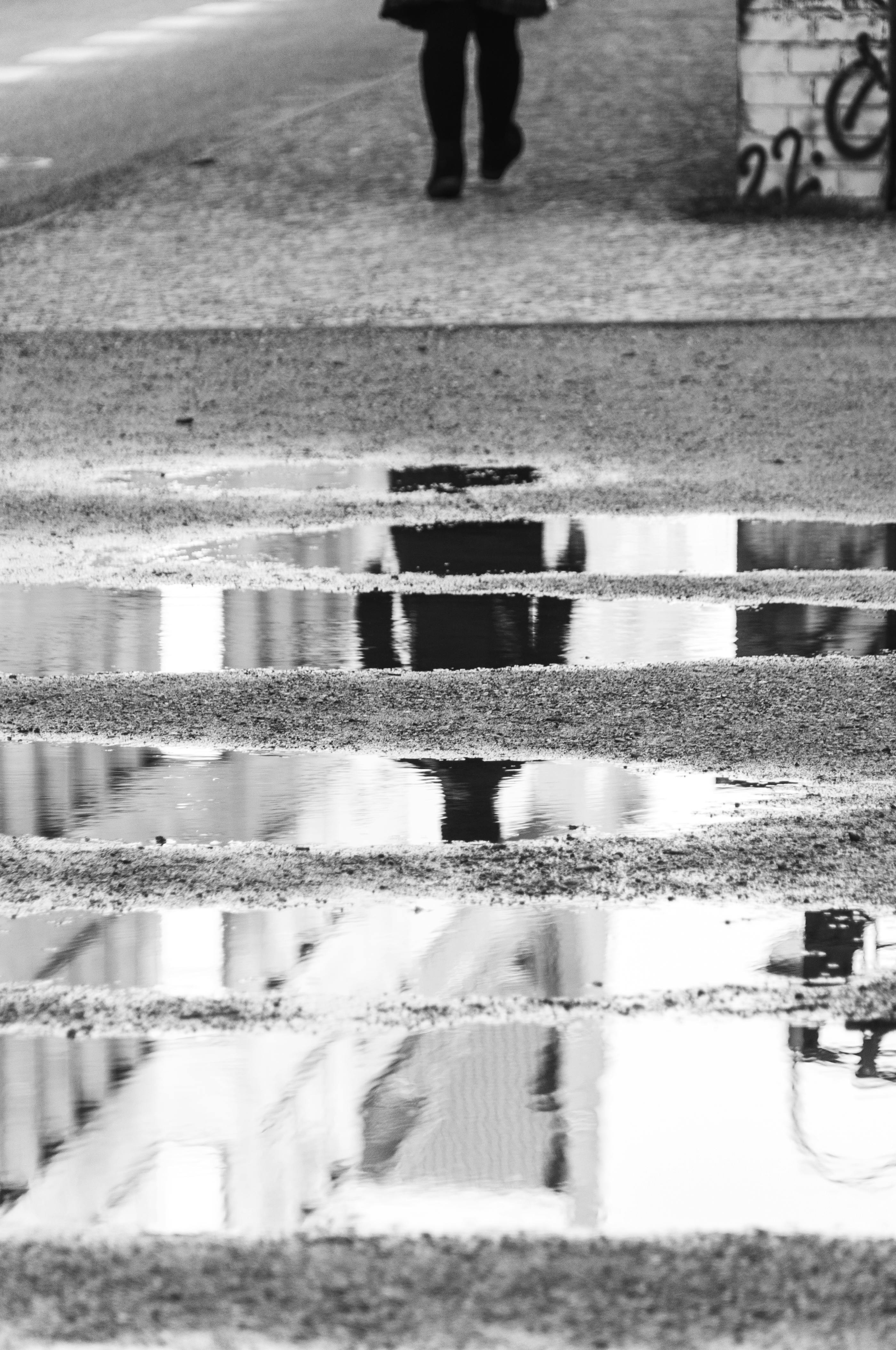 Gratis Et sort-hvidt billede, der indfanger et reflekterende bybillede med en ensom fodgænger Lagerfoto