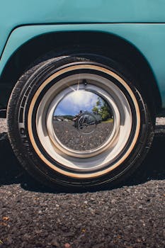 Vintage car wheel reflecting surrounding scenery with a person taking a photo.