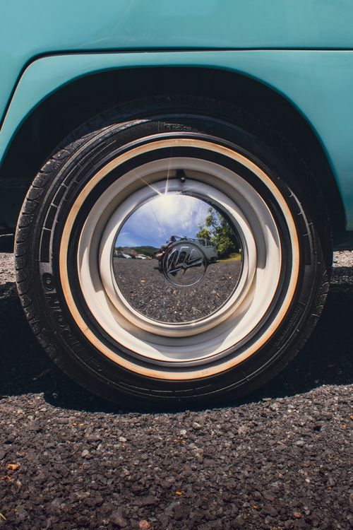 Free Vintage car wheel reflecting surrounding scenery with a person taking a photo. Stock Photo