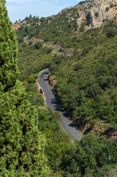 Winding road in lush green valley with cars and distant houses. Perfect for travel and nature themes.