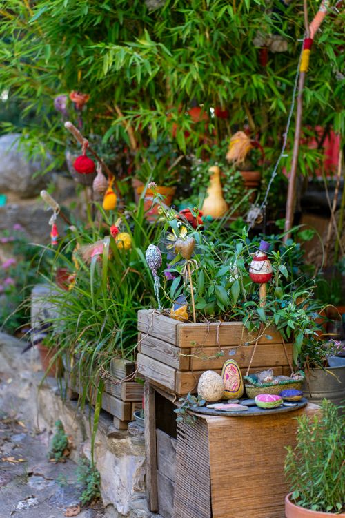 Free A colorful garden display with plants, wooden crates, and decorative ornaments in an outdoor setting. Stock Photo