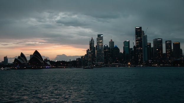 Stunning view of Sydney's skyline with the Opera House at sunset, capturing the city's iconic architecture against a dramatic sky.