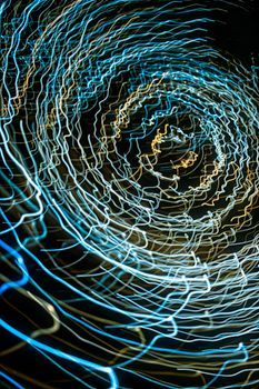 Abstract image of swirling blue and gold light trails creating a dynamic spiral pattern against a dark background.