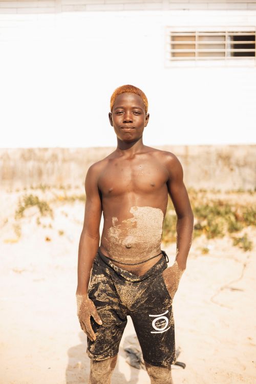 Free A teenage boy covered in sand enjoys a sunny day at the beach in Freetown, Sierra Leone. Stock Photo