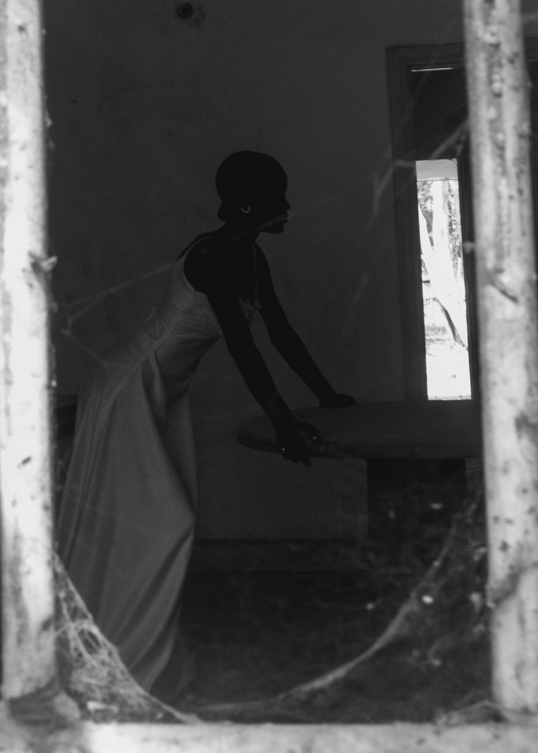 Ücretsiz Nijerya'nın Zaria kentinde, örümcek ağlarıyla kaplı bir pencereden görünen bir kadının sanatsal siyah beyaz silüeti. Stok Fotoğraflar