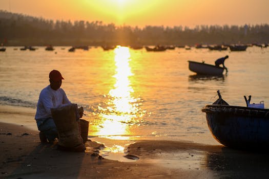 A serene morning scene of fishermen at Đà Nẵng beach during sunrise, capturing daily life in Vietnam.