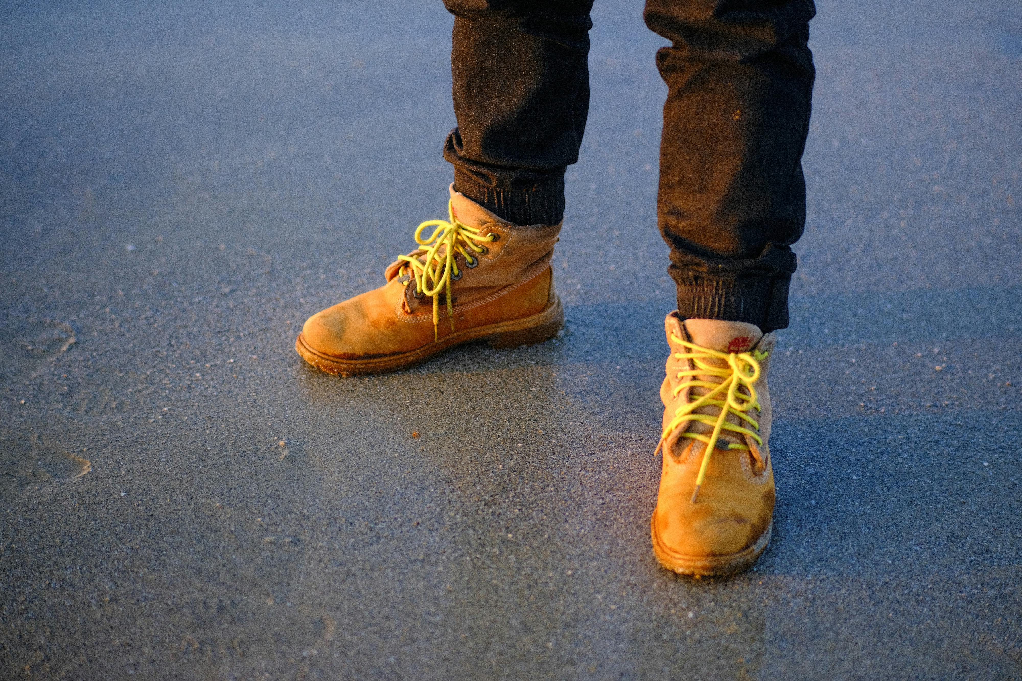 ฟรี ภาพระยะใกล้ของรองเท้าปีนเขาสีเหลืองบนผืนทรายเปียกขณะพระอาทิตย์ขึ้นในเมืองดานัง ประเทศเวียดนาม คลังภาพถ่าย