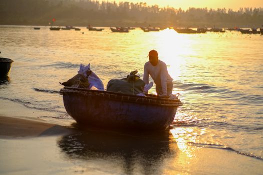 A fisherman on My Khe Beach, Đà Nẵng, during sunrise, preparing for a day at sea.