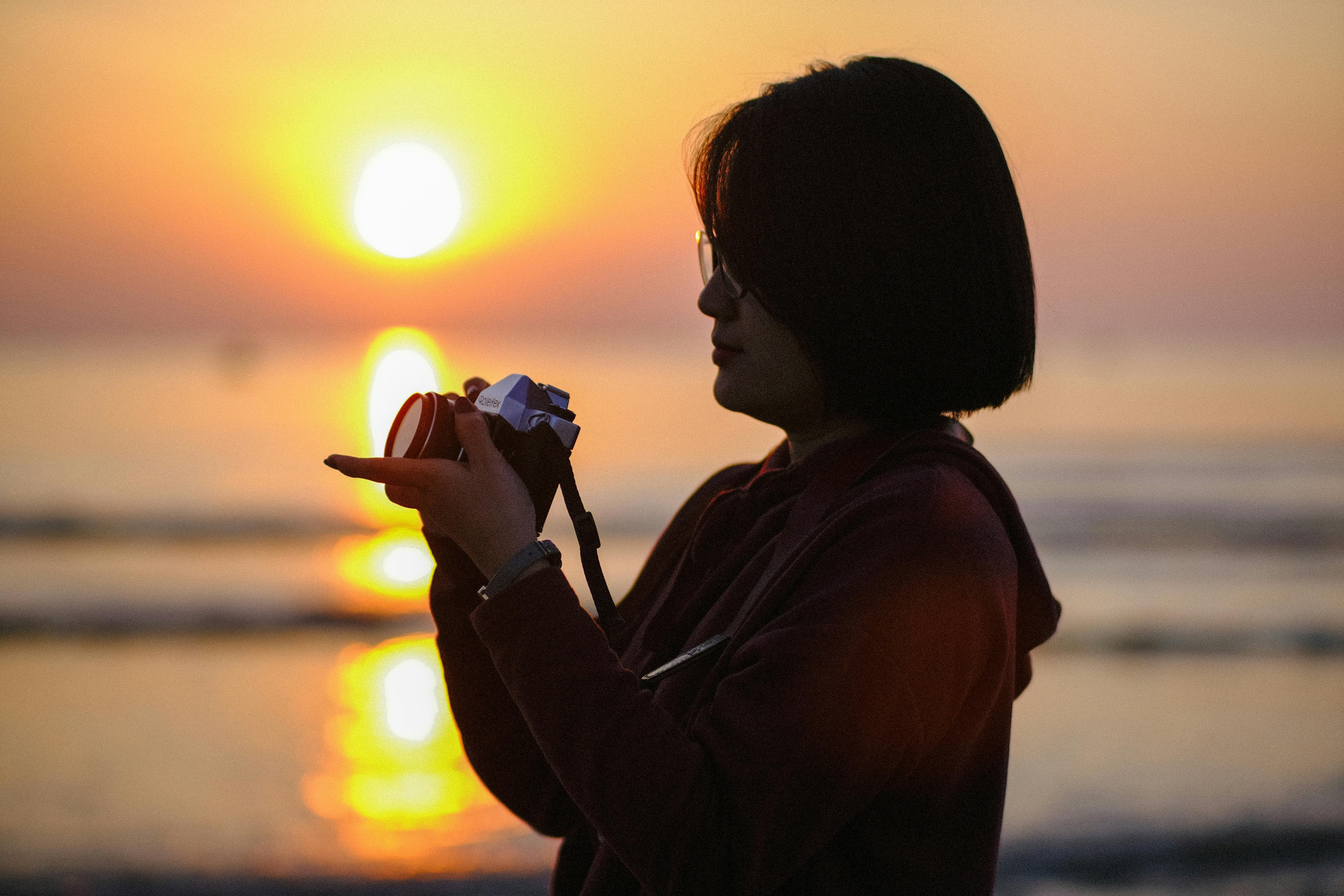 Gratis Silhouette di una persona che fotografa l'alba su una spiaggia a Đà Nẵng, Vietnam. Foto a disposizione