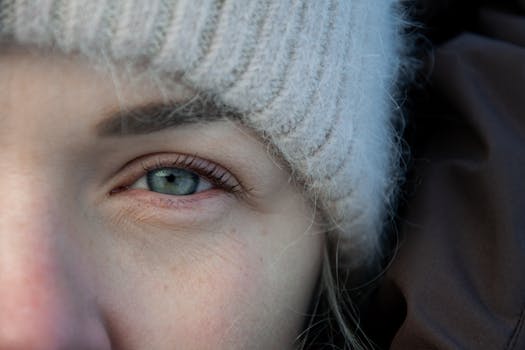 Close-up of a woman's eye framed by a cozy winter hat, capturing subtle details.