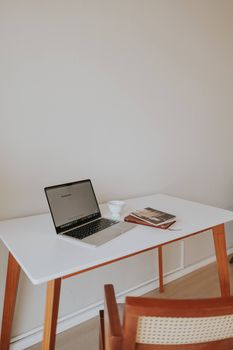 Clean and simple home office setup featuring a laptop, notebook, and coffee on a minimalist wooden desk.