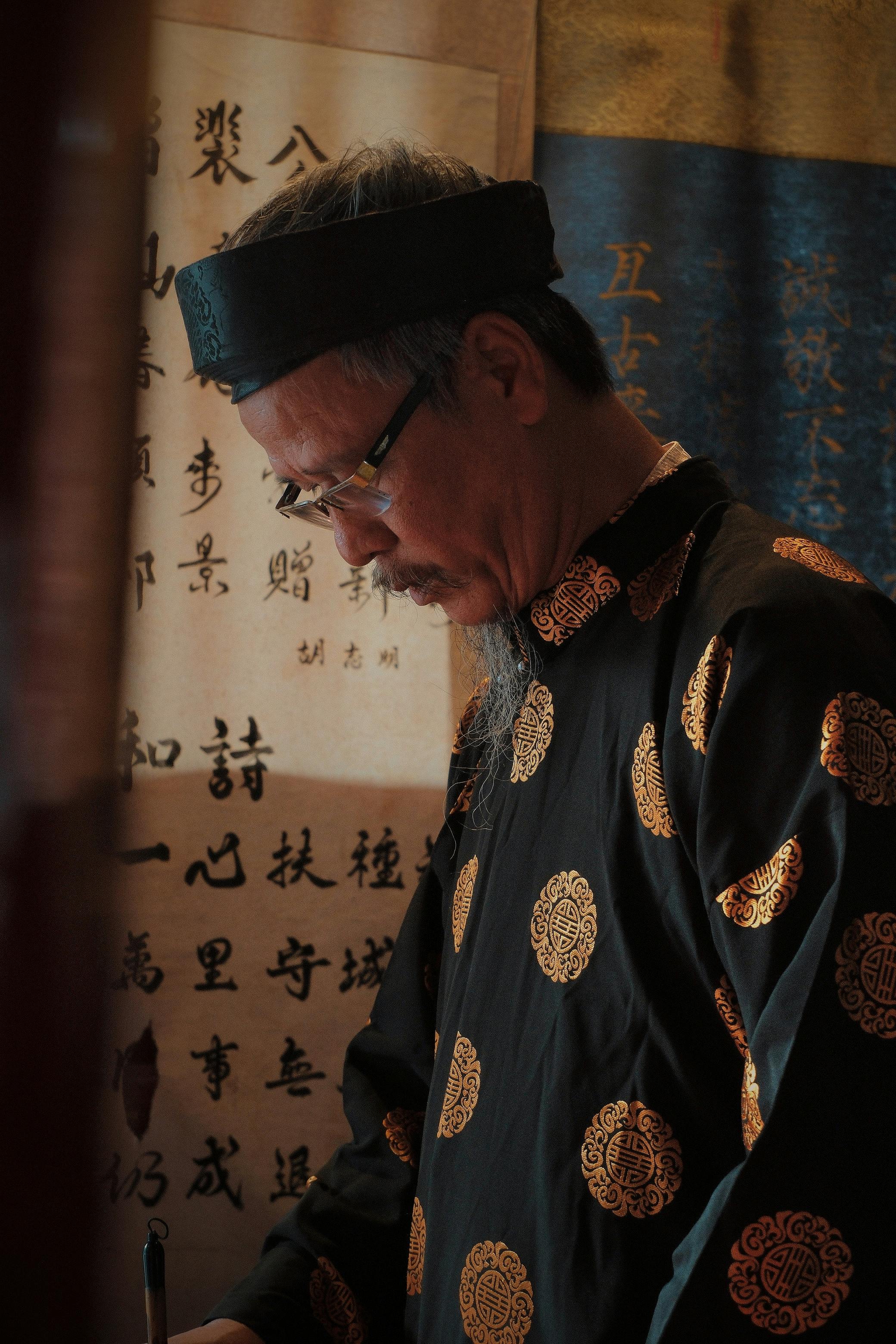 Elderly Vietnamese man practicing traditional calligraphy in Hanoi.