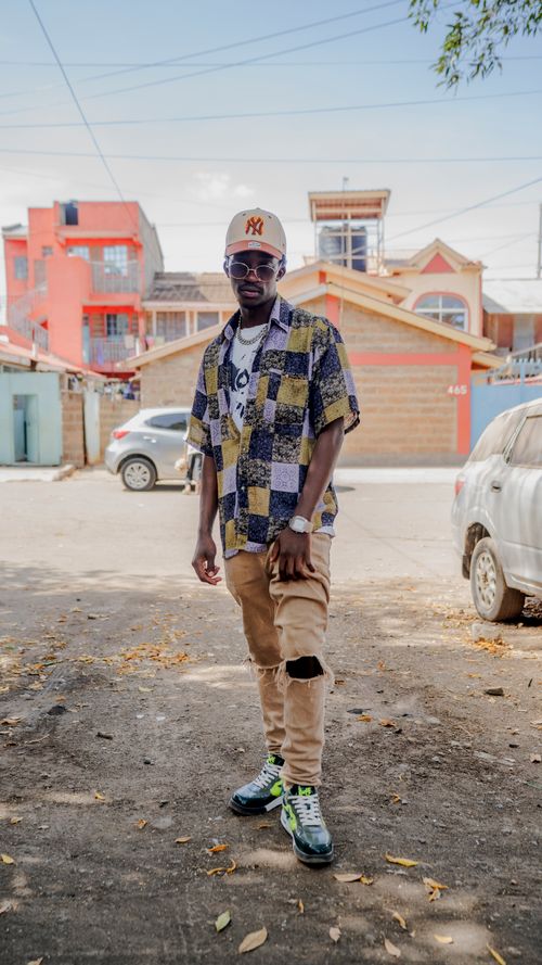 Free A fashionable young man poses confidently in a vibrant Nairobi neighborhood. Stock Photo